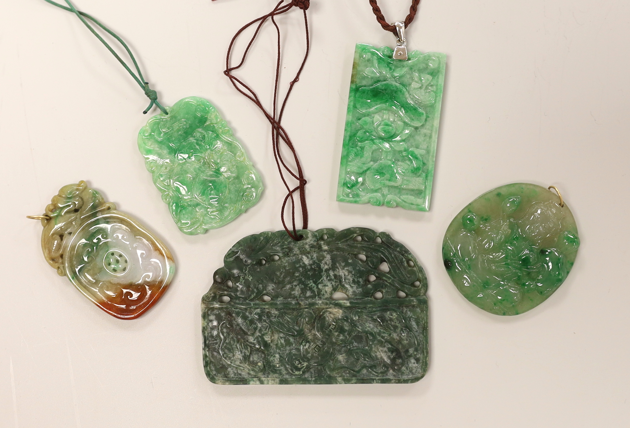 Five assorted jadeite pendants, largest 8cm wide